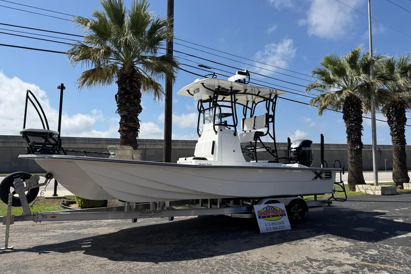 Slide: The Image of 2026 Shallow Sport 25 X3 boat on trailer, parked near palm trees under a clear sky. - 59