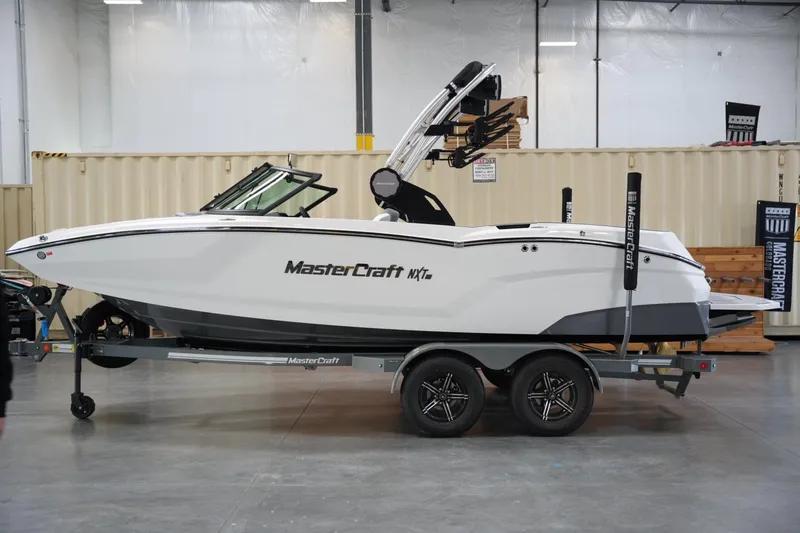 The Image of 2025 MasterCraft NXT20 boat on trailer in indoor showroom setting. - 1