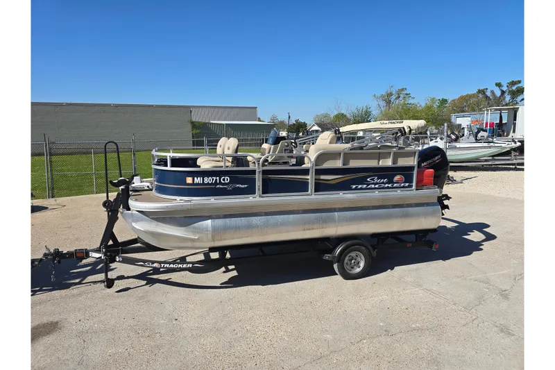 The Image of 2024 Sun Tracker Bass Buggy 16 XL Select pontoon boat on trailer in outdoor setting. - 1