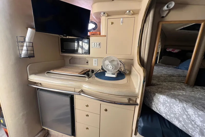 Slide: The Image of Interior of 1998 Sea Ray 290 Sundancer with kitchenette, TV, and sleeping area. - 16