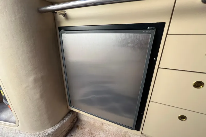 Slide: The Image of 1998 Sea Ray 290 Sundancer interior with stainless steel refrigerator and beige cabinetry. - 19