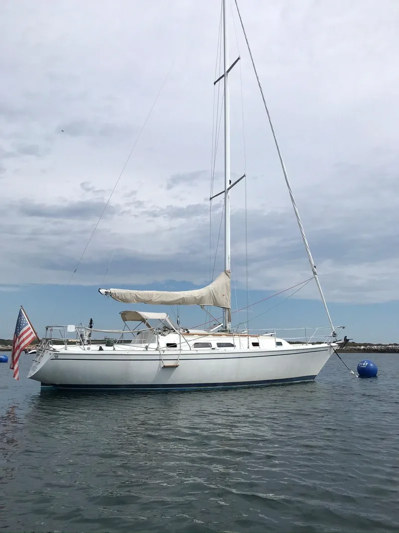 Slide: The Image of 1988 Ericson 34 sailboat anchored on calm water with an American flag. - 3