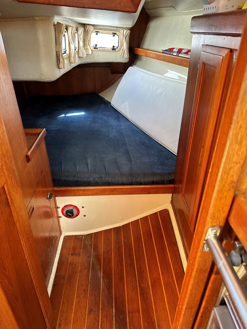 Slide: The Image of 1988 Ericson 34 sailboat cabin with wooden flooring and cozy sleeping area. - 9