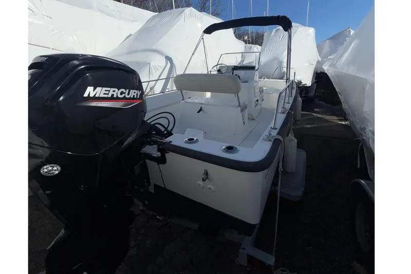 Slide: The Image of 2020 Boston Whaler 170 Montauk boat with Mercury engine, docked outdoors. - 2