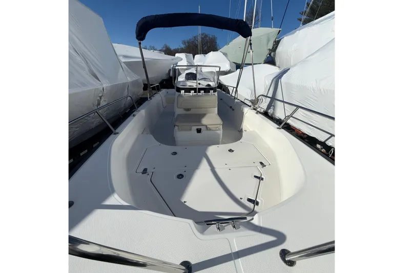 Slide: The Image of 2020 Boston Whaler 170 Montauk boat with blue canopy, docked under clear sky. - 4
