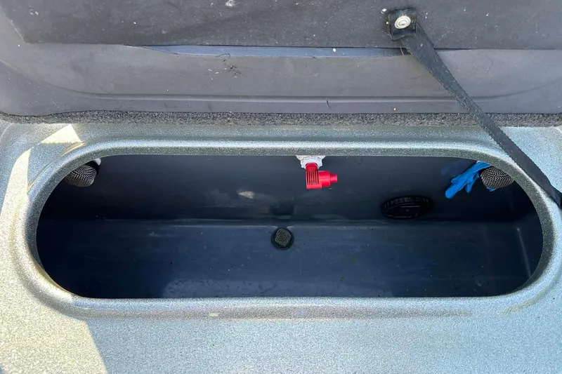 Slide: The Image of Open storage compartment in 2018 Yar-Craft 219TFX boat, featuring a red valve and blue glove. - 37