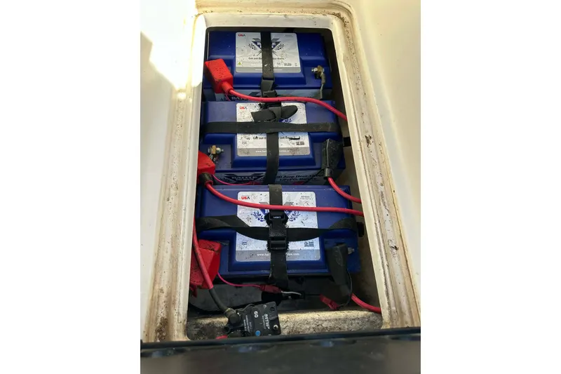 Slide: The Image of 2018 Yar-Craft 219TFX boat battery compartment with secured blue batteries and red cables. - 52