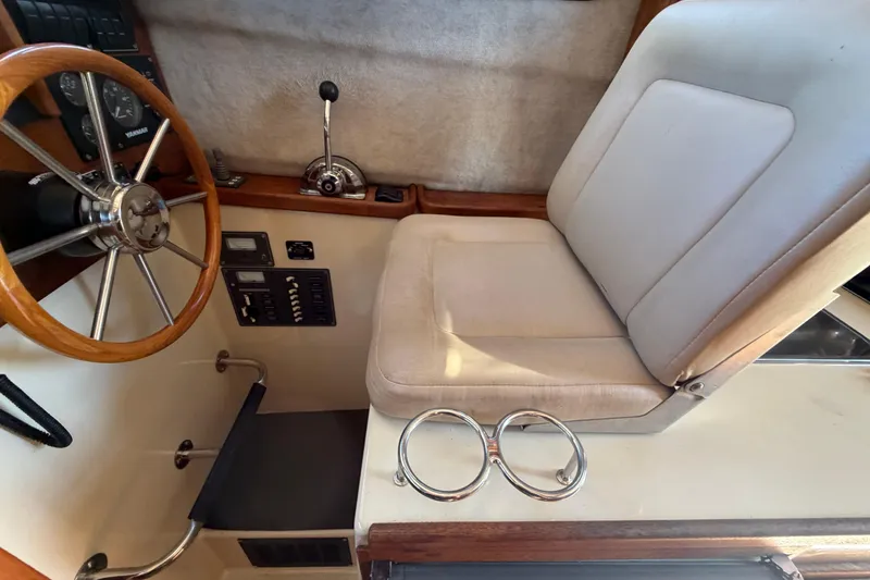 Slide: The Image of 2008 Ranger Tugs R-25 helm with steering wheel, controls, and cushioned seat. - 13