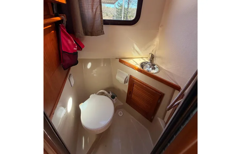 Slide: The Image of Compact bathroom in 2008 Ranger Tugs R-25 boat with toilet, sink, and window. - 16