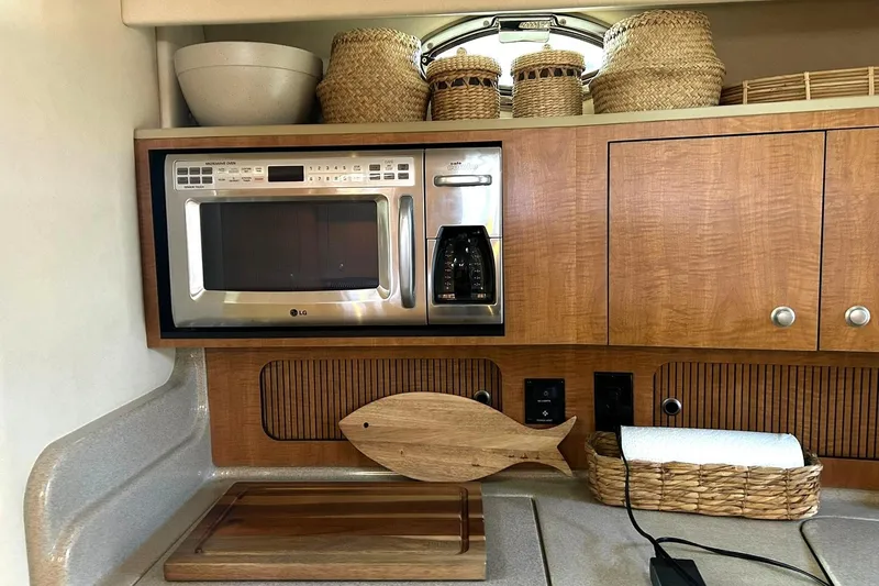 Slide: The Image of 2006 Sea Ray Sundancer 320 galley with microwave, coffee maker, and wooden fish decor. - 46