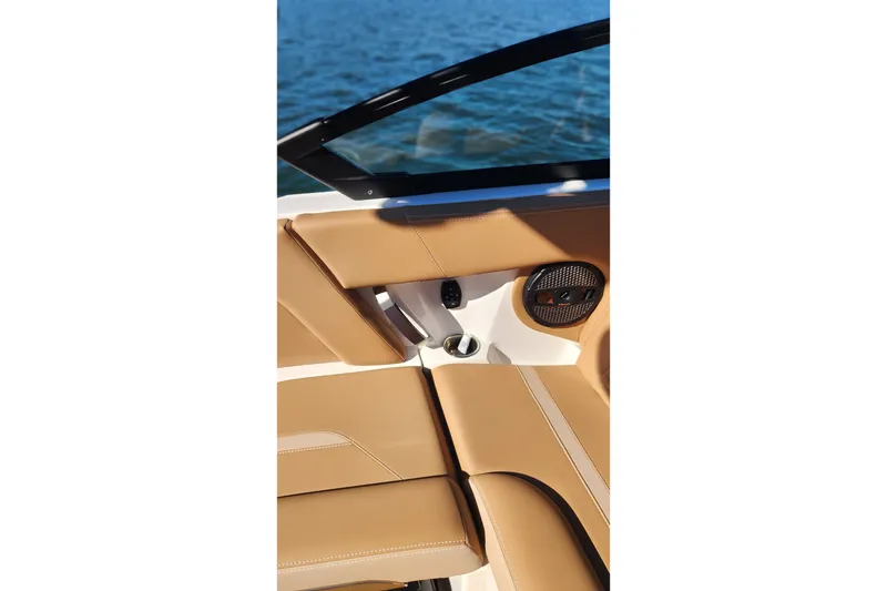 Slide: The Image of 2024 MasterCraft X24 boat interior with tan leather seats and speaker, overlooking water. - 11