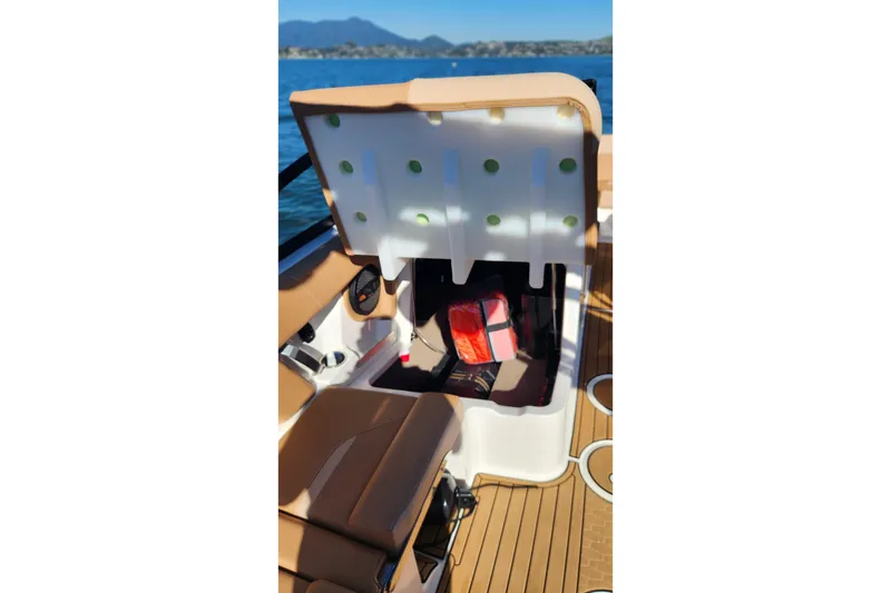 Slide: The Image of 2024 MasterCraft X24 boat interior storage compartment with open lid on a sunny day. - 12