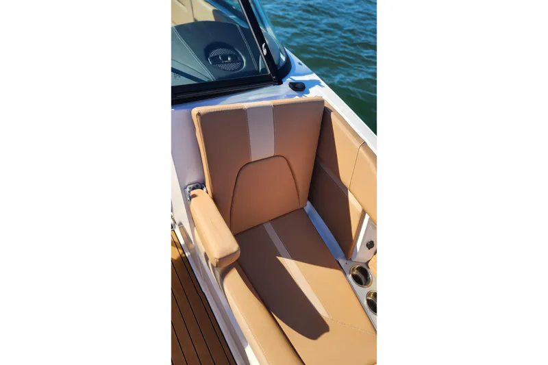 Slide: The Image of 2024 MasterCraft X24 boat interior with tan seating and cup holders by the water. - 14