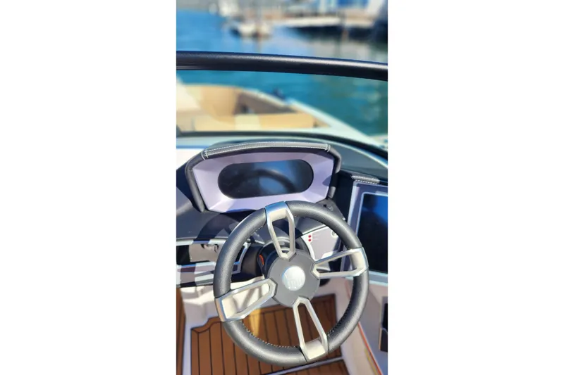 Slide: The Image of 2024 MasterCraft X24 boat steering wheel and dashboard, docked by the water. - 16