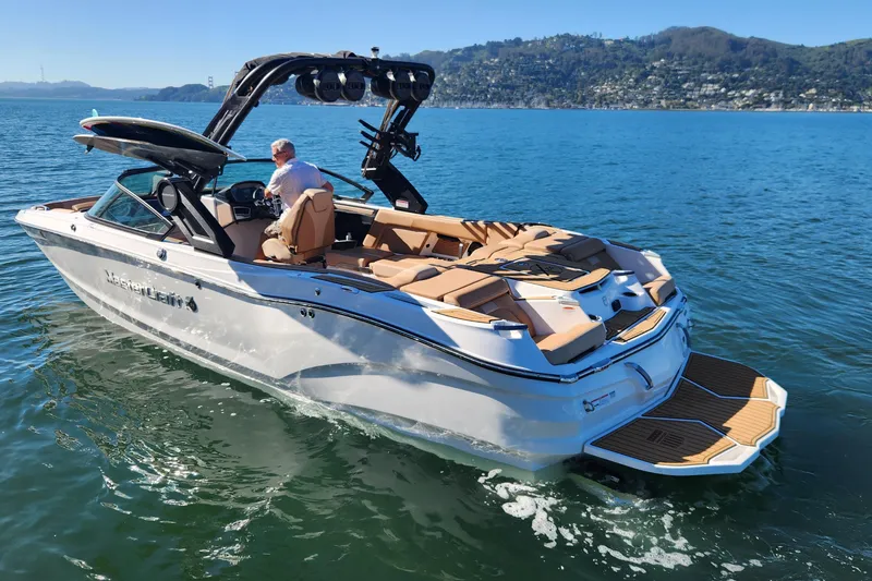 Slide: The Image of 2024 MasterCraft X24 boat cruising on a scenic lake with mountains in the background. - 26