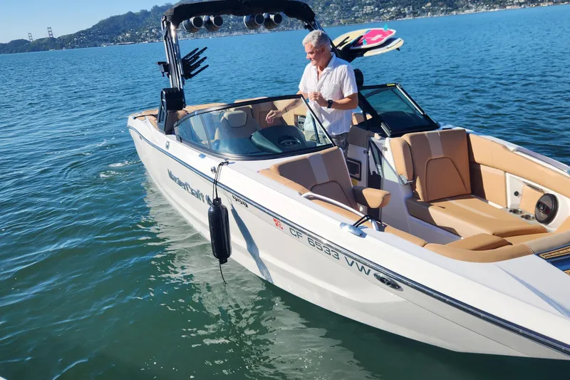 Slide: The Image of 2024 MasterCraft X24 boat on water with a person onboard, scenic background. - 28