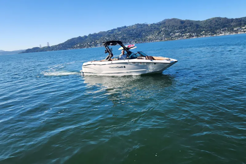 Slide: The Image of 2024 MasterCraft X24 boat cruising on a scenic lake with hills in the background. - 30