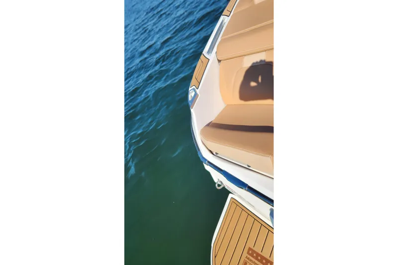 Slide: The Image of 2024 MasterCraft X24 boat with tan seating, docked on calm blue water. - 32