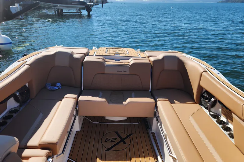 Slide: The Image of Luxurious 2024 MasterCraft X24 boat interior with tan seating, docked on a sunny day. - 4