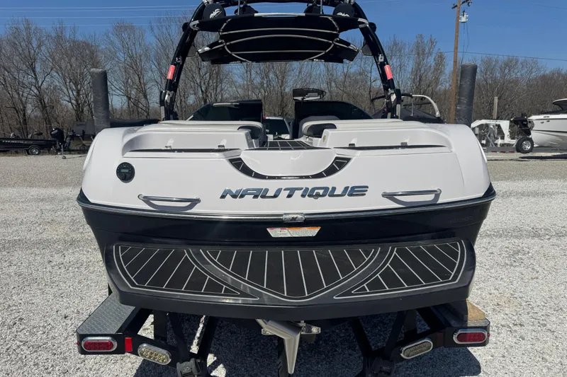 Slide: The Image of 2011 Nautique Super Air Nautique 230 boat, rear view, parked on gravel lot. - 11