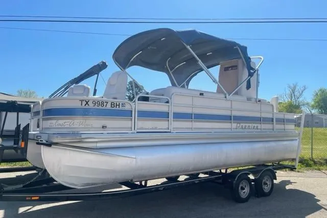 The Image of 2009 Premier 221 Cast-A-Way pontoon boat on trailer, featuring blue canopy and white seating. - 0