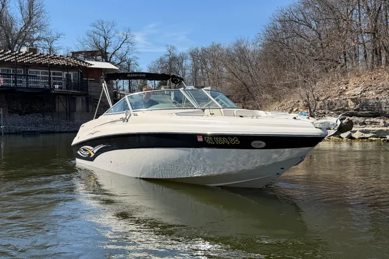 The Image of 2003 Rinker 282 Captiva Bowrider on calm water near a lakeside house. - 1