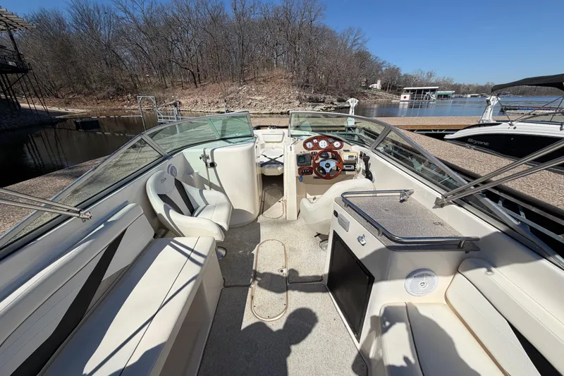 Slide: The Image of 2003 Rinker 282 Captiva Bowrider interior with seating and helm, docked by a lake. - 15