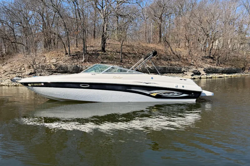 Slide: The Image of 2003 Rinker 282 Captiva Bowrider on calm water, surrounded by bare trees. - 4
