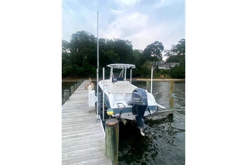 Slide: The Image of 2020 Sea Hunt Ultra 225 boat docked by a serene waterfront with Yamaha engine. - 2