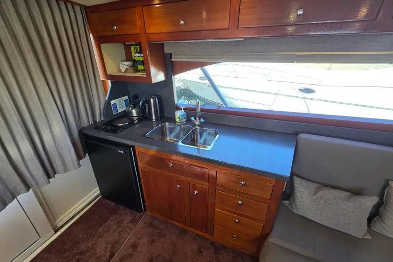 Slide: The Image of 2002 Luhrs 34 Convertible yacht interior with kitchenette, featuring wooden cabinets and dual sinks. - 19