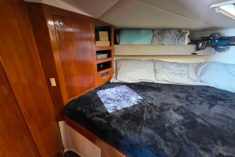 Slide: The Image of Cozy cabin interior of 2002 Luhrs 34 Convertible with wooden cabinetry and plush bedding. - 22
