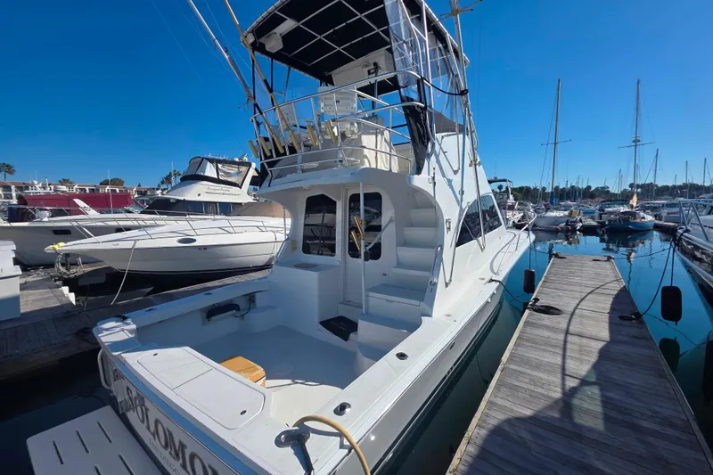 Slide: The Image of 2002 Luhrs 34 Convertible yacht docked at marina, showcasing spacious deck and flybridge. - 27