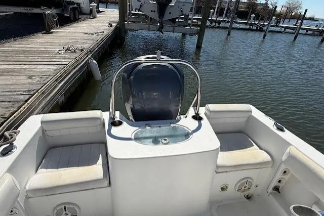 Slide: The Image of 2012 Sea Hunt Triton 225 boat interior with seating and motor at dock. - 10