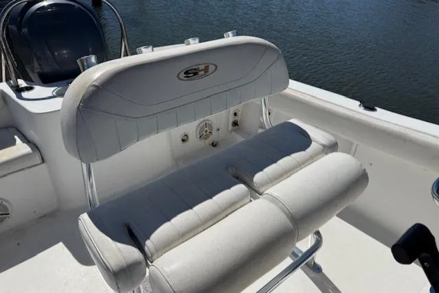 Slide: The Image of 2012 Sea Hunt Triton 225 boat seat with white upholstery and water backdrop. - 11