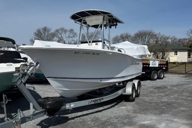 Slide: The Image of 2012 Sea Hunt Triton 225 boat on trailer, parked outdoors under clear sky. - 3