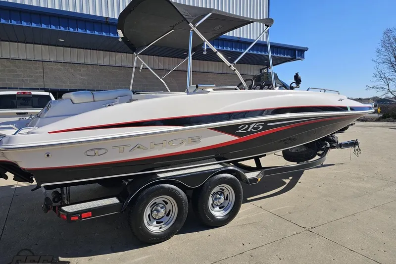 Slide: The Image of 2015 Tahoe 215 Xi boat on trailer, parked outdoors under clear sky. - 10