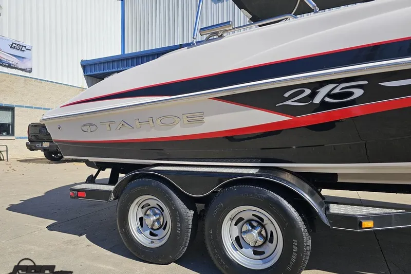Slide: The Image of 2015 Tahoe 215 Xi boat on trailer, featuring sleek design and vibrant red accents. - 12