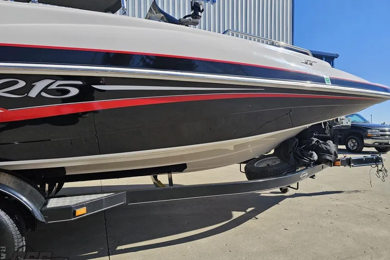 Slide: The Image of 2015 Tahoe 215 Xi boat on trailer, featuring sleek black and red design. - 13