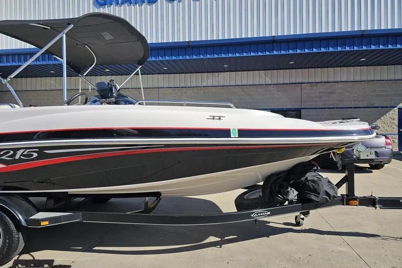 Slide: The Image of 2015 Tahoe 215 Xi boat on trailer, parked outside a building. - 16