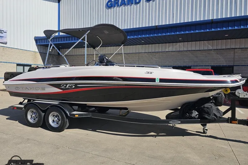 Slide: The Image of 2015 Tahoe 215 Xi boat on trailer outside a building, featuring sleek design and canopy. - 17