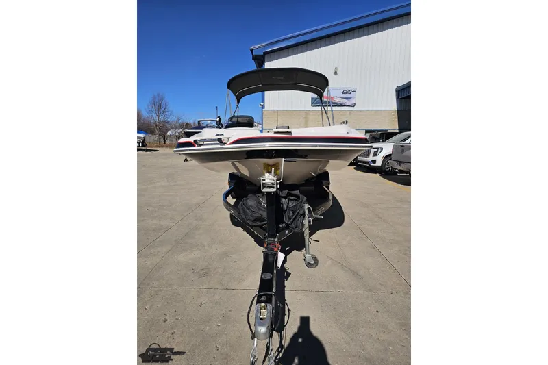 Slide: The Image of 2015 Tahoe 215 Xi boat on trailer, parked outdoors under clear blue sky. - 22