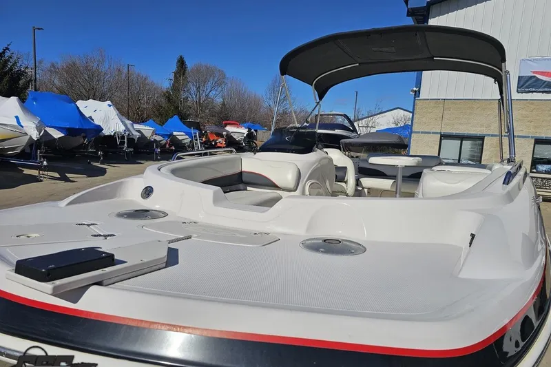 Slide: The Image of 2015 Tahoe 215 Xi boat with canopy, parked outdoors under clear blue sky. - 25