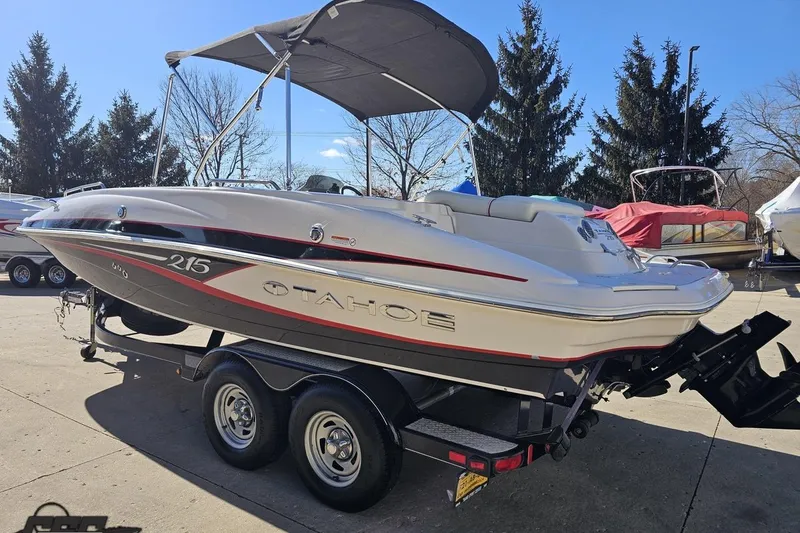 Slide: The Image of 2015 Tahoe 215 Xi boat on trailer, parked outdoors under clear sky. - 30