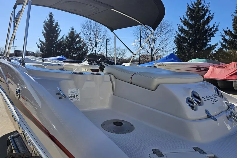 Slide: The Image of 2015 Tahoe 215 Xi boat with canopy, parked outdoors under clear sky. - 32
