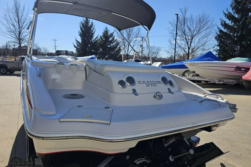 Slide: The Image of 2015 Tahoe 215 Xi boat with canopy, parked outdoors on a sunny day. - 33