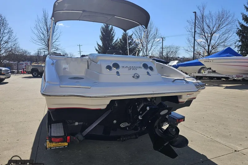 Slide: The Image of 2015 Tahoe 215 Xi boat with canopy, parked outdoors on a sunny day. - 34