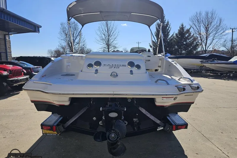 Slide: The Image of 2015 Tahoe 215 Xi boat with canopy, parked outdoors on a sunny day. - 35