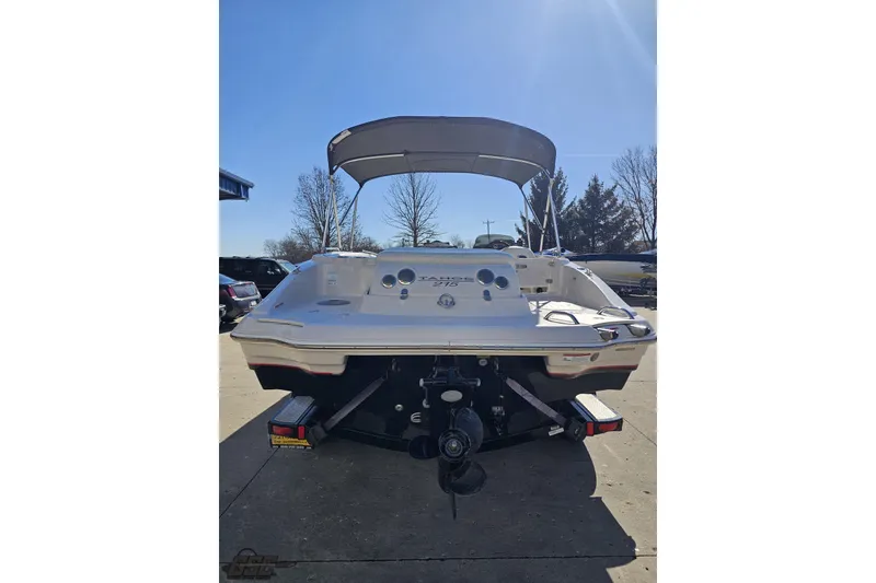 Slide: The Image of 2015 Tahoe 215 Xi boat, rear view with canopy, parked outdoors under clear sky. - 36