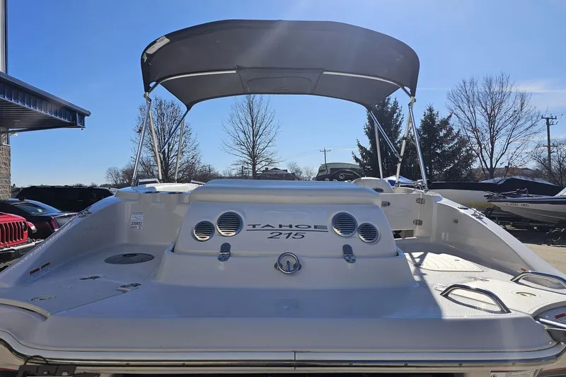 Slide: The Image of 2015 Tahoe 215 Xi boat with canopy, parked outdoors under clear blue sky. - 38