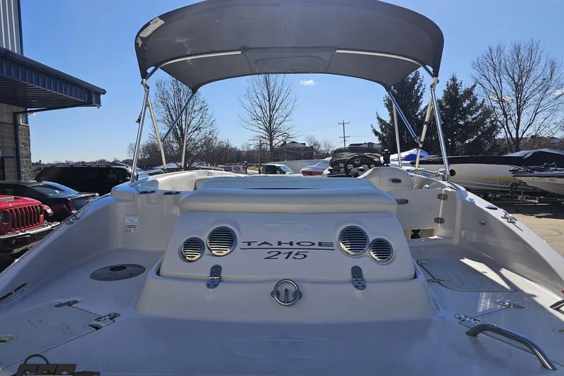 Slide: The Image of 2015 Tahoe 215 Xi boat with canopy, parked outdoors under clear blue sky. - 39